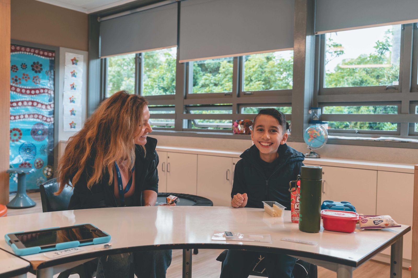 Teachers aide and student sharing morning tea time together